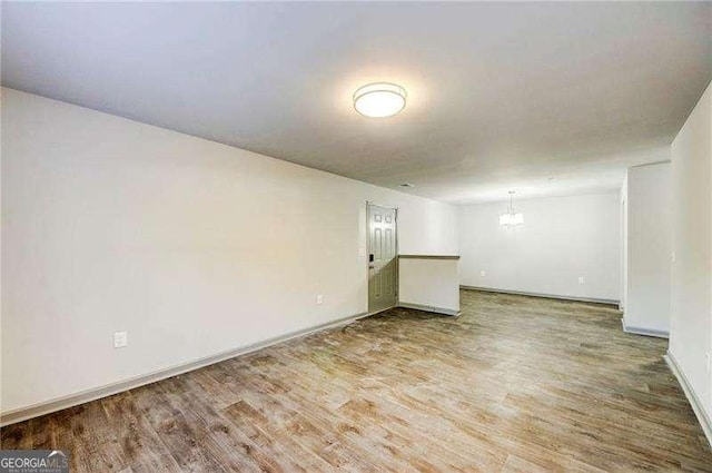 unfurnished room featuring a chandelier and wood-type flooring