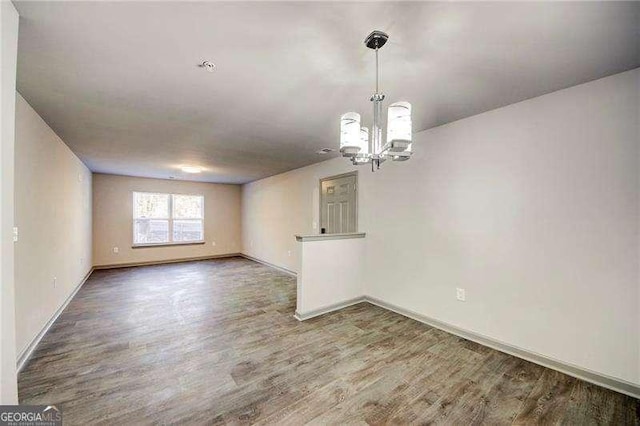 spare room featuring wood-type flooring and an inviting chandelier