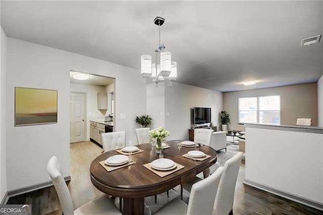 dining area featuring light wood-type flooring and a chandelier