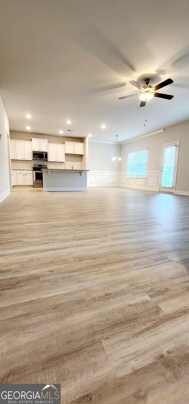 unfurnished living room featuring ceiling fan and light hardwood / wood-style floors