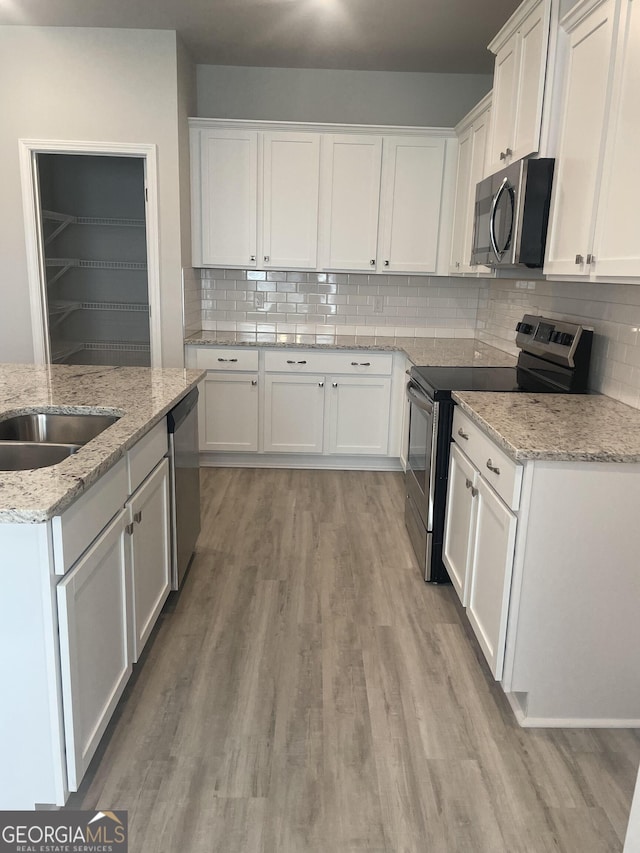 kitchen featuring white cabinets, appliances with stainless steel finishes, tasteful backsplash, and light stone countertops