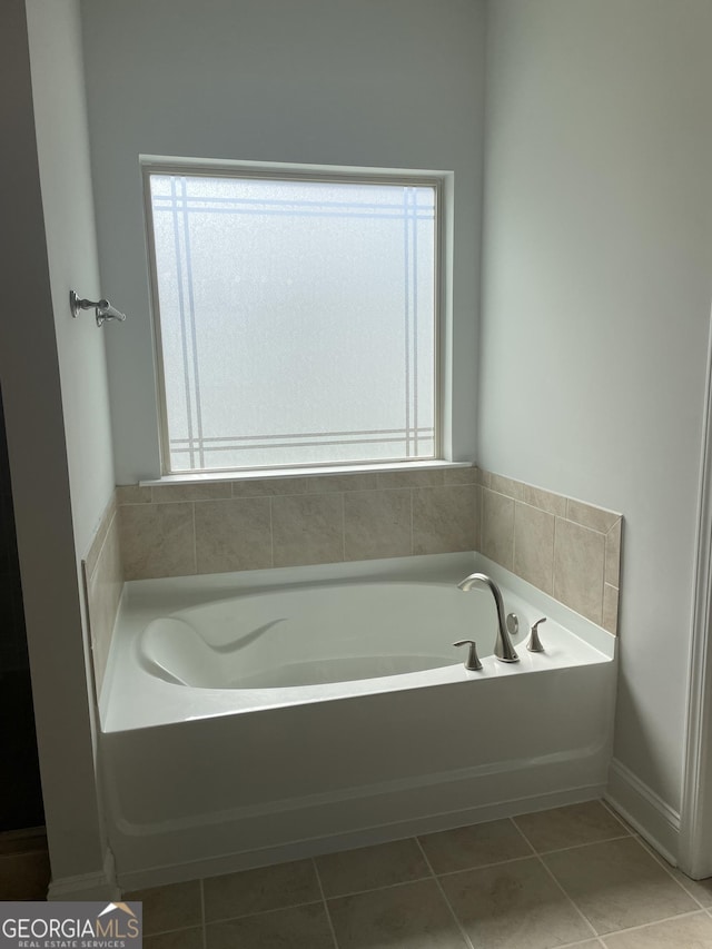 bathroom featuring tile patterned flooring, a tub, and a wealth of natural light