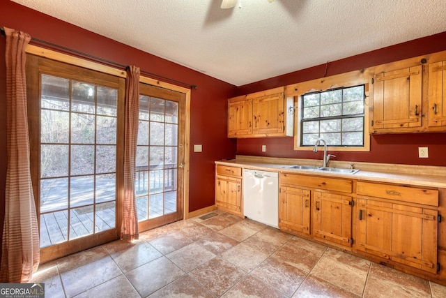 kitchen featuring ceiling fan, dishwasher, sink, a healthy amount of sunlight, and a textured ceiling