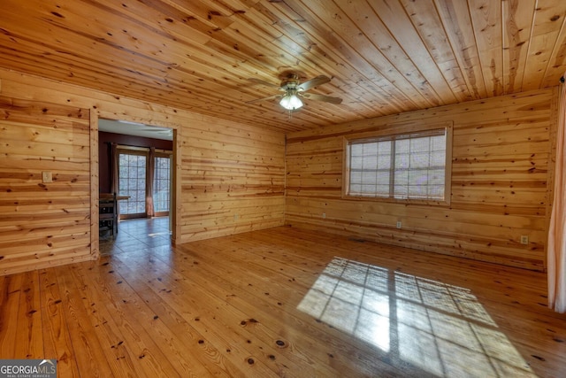 unfurnished room featuring ceiling fan, wood walls, light wood-type flooring, and wooden ceiling