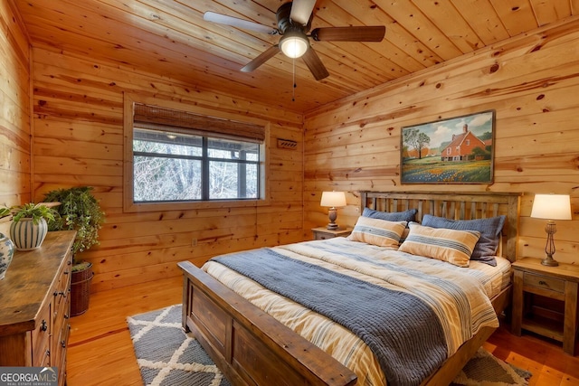 bedroom with light hardwood / wood-style floors, wooden ceiling, and wooden walls