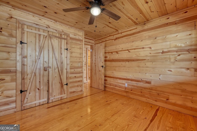 empty room featuring hardwood / wood-style flooring, ceiling fan, wooden ceiling, and wooden walls