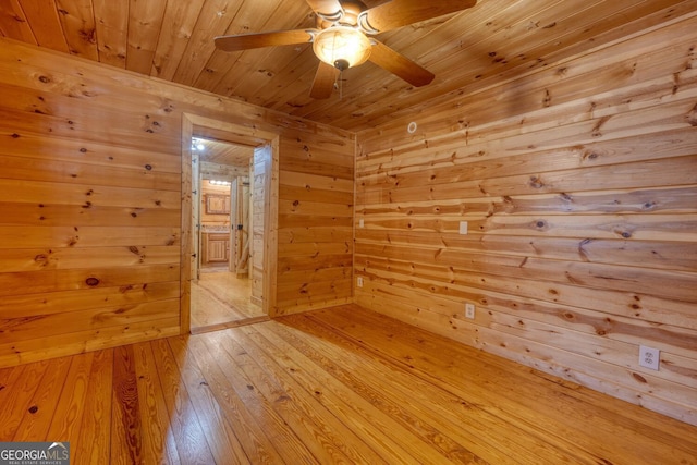 unfurnished room with ceiling fan, wood walls, light hardwood / wood-style floors, and wooden ceiling