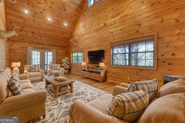 living room featuring wood walls, light wood-type flooring, and high vaulted ceiling