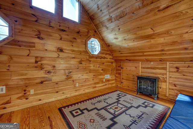 interior space with a wood stove, wooden walls, vaulted ceiling, hardwood / wood-style flooring, and wood ceiling