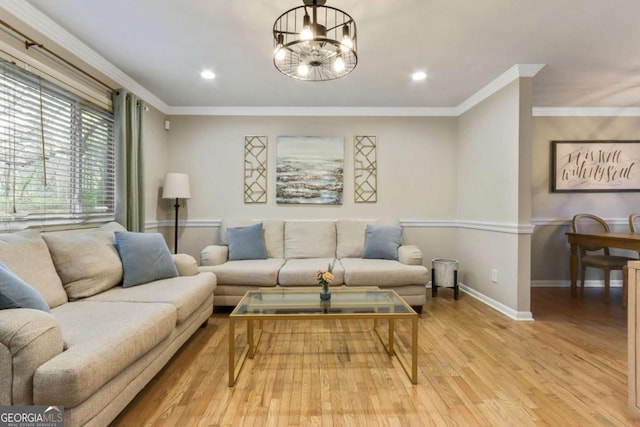 living room featuring crown molding, light hardwood / wood-style floors, and an inviting chandelier