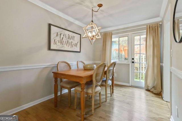 dining area with ornamental molding, light hardwood / wood-style floors, french doors, and a notable chandelier