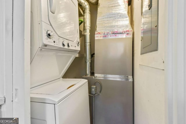 laundry area featuring electric panel and stacked washer and clothes dryer