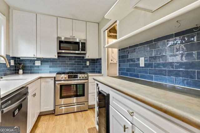 kitchen featuring stainless steel appliances, white cabinetry, tasteful backsplash, and sink