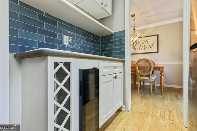 kitchen featuring white cabinetry, hanging light fixtures, backsplash, crown molding, and light hardwood / wood-style floors