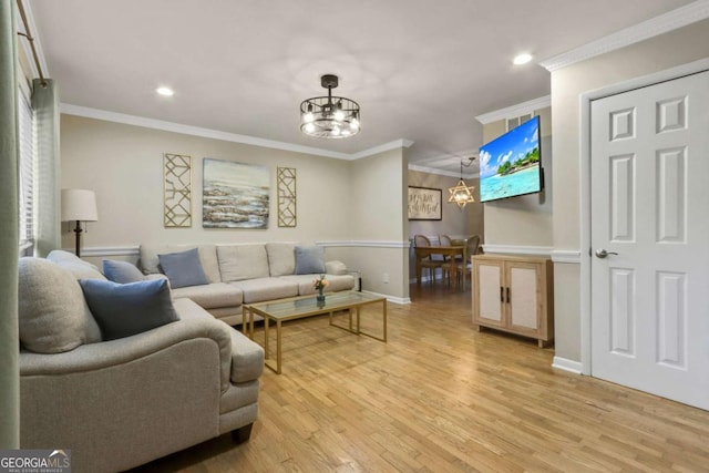 living room featuring ornamental molding, light wood-type flooring, and a notable chandelier