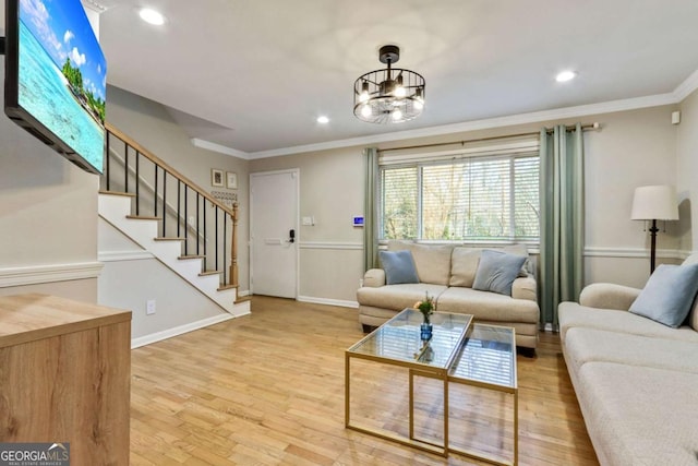 living room with a chandelier, light wood-type flooring, and crown molding