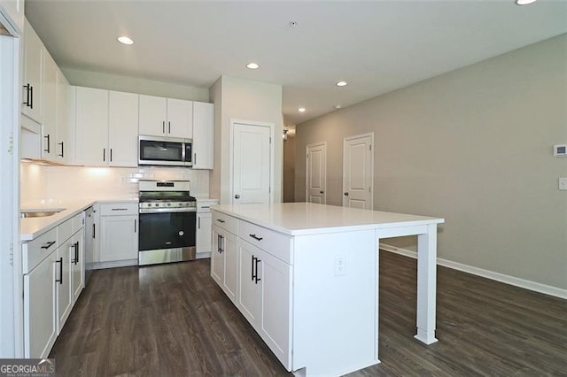 kitchen featuring white cabinets, a kitchen island, stainless steel appliances, and dark wood-type flooring