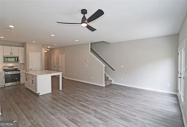 kitchen with a kitchen breakfast bar, stainless steel appliances, ceiling fan, white cabinets, and a kitchen island