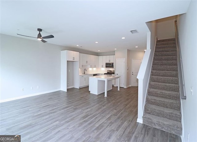 kitchen featuring appliances with stainless steel finishes, a breakfast bar, ceiling fan, a center island, and white cabinetry