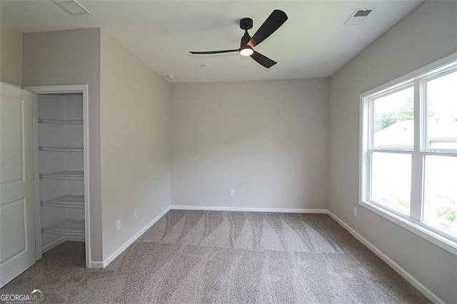 empty room featuring light carpet, a wealth of natural light, and ceiling fan