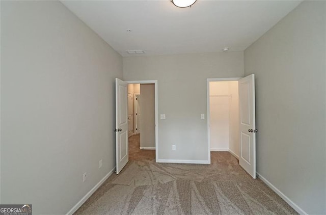 unfurnished bedroom with light colored carpet, a spacious closet, and a closet