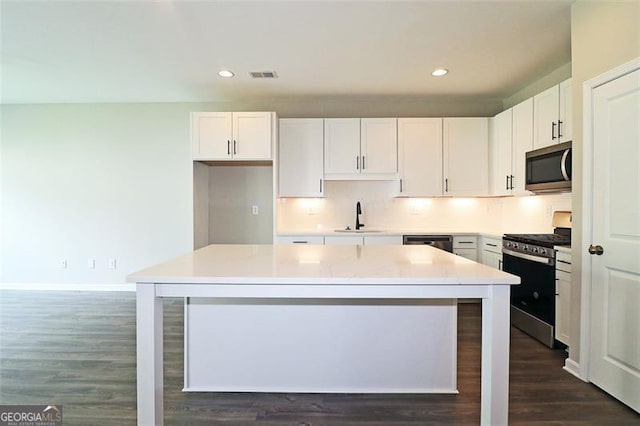 kitchen featuring a center island, sink, appliances with stainless steel finishes, dark hardwood / wood-style flooring, and white cabinetry