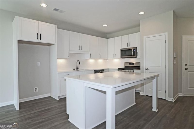 kitchen with white cabinets, sink, a kitchen island, dark hardwood / wood-style flooring, and stainless steel appliances