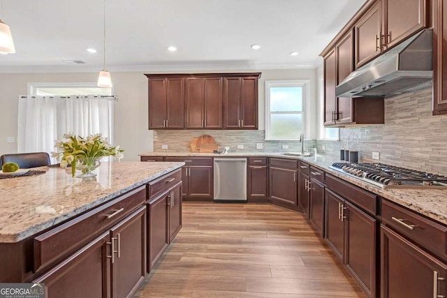 kitchen with pendant lighting, backsplash, sink, crown molding, and appliances with stainless steel finishes