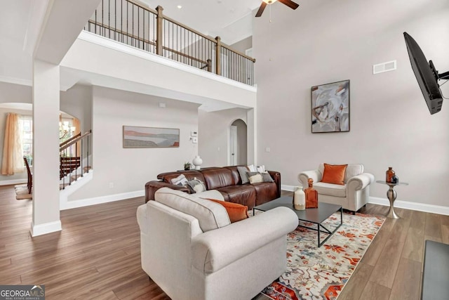 living room featuring ceiling fan with notable chandelier, a towering ceiling, and dark hardwood / wood-style floors