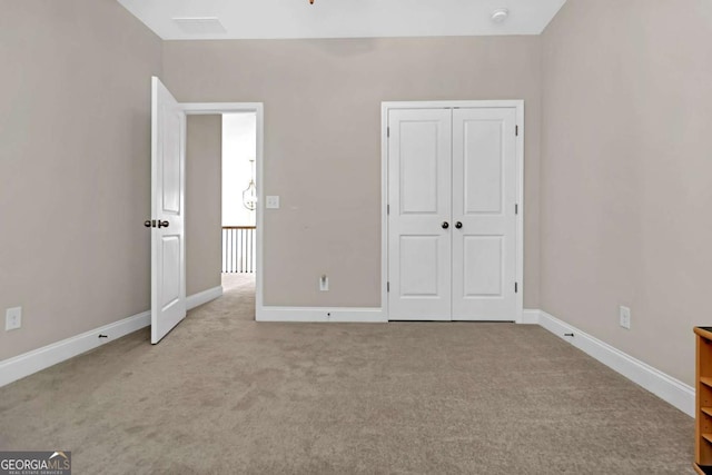 unfurnished bedroom featuring light carpet and a closet