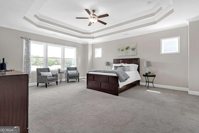 carpeted bedroom featuring a tray ceiling and ceiling fan