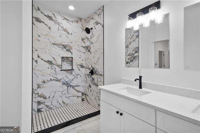 bathroom with a tile shower and vanity