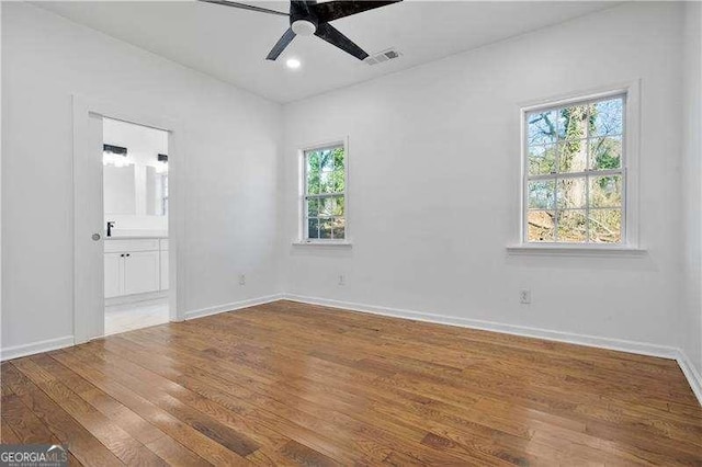 spare room featuring a healthy amount of sunlight, ceiling fan, and wood-type flooring