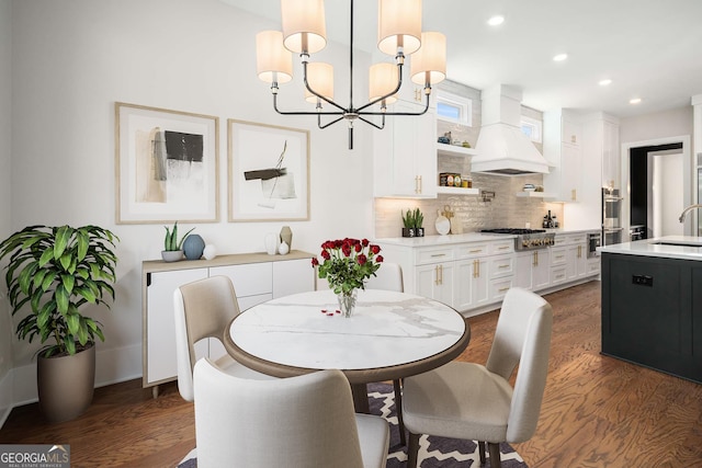 dining space with sink, dark hardwood / wood-style floors, and a chandelier