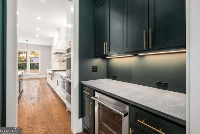 kitchen featuring premium range hood, wine cooler, white cabinets, and light hardwood / wood-style flooring