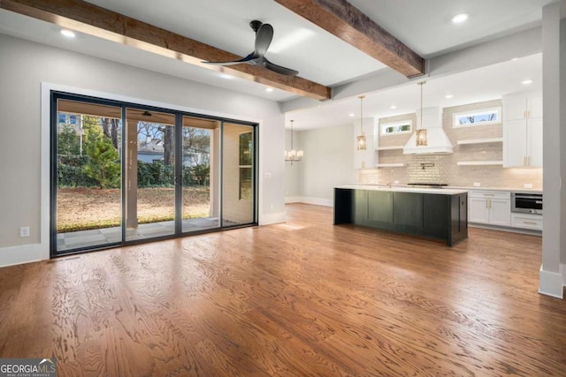 kitchen featuring custom exhaust hood, white cabinetry, tasteful backsplash, a kitchen island, and pendant lighting