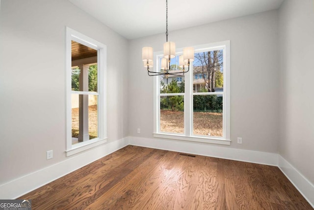 unfurnished dining area featuring hardwood / wood-style floors and an inviting chandelier