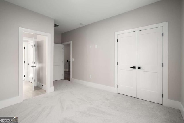 unfurnished bedroom featuring light carpet and a closet