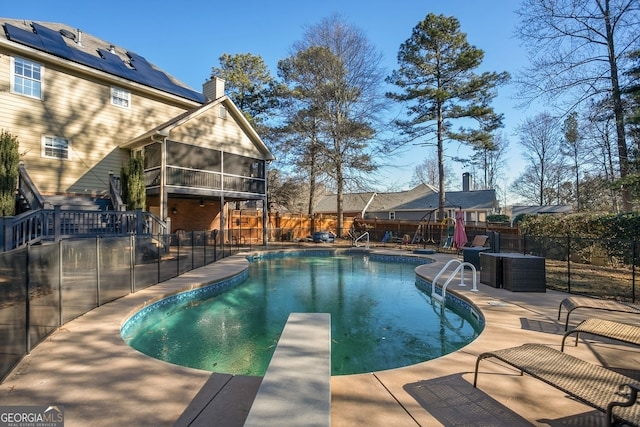 view of swimming pool featuring a patio, a diving board, and a sunroom