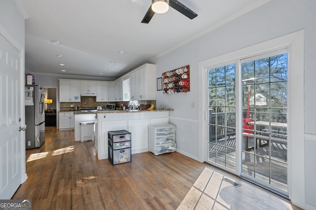 kitchen featuring dark wood-type flooring, white cabinets, decorative backsplash, kitchen peninsula, and stainless steel appliances