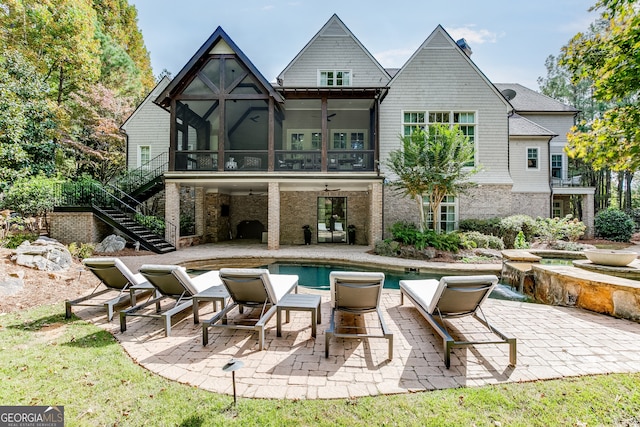 rear view of property featuring ceiling fan, a pool with hot tub, a patio area, and a sunroom