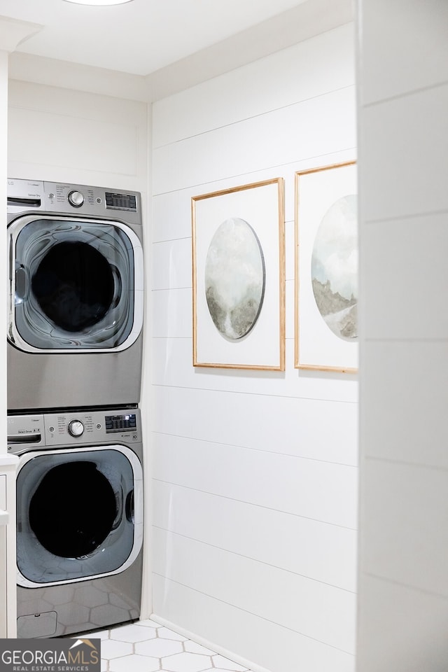 clothes washing area with wooden walls and stacked washer / dryer