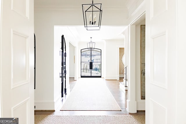 hallway with ornamental molding, a chandelier, and light hardwood / wood-style flooring