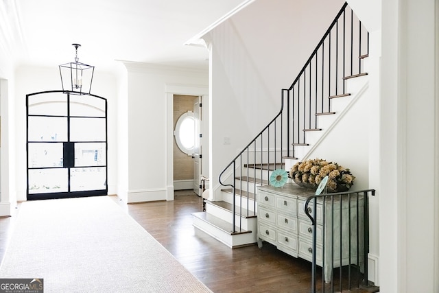 entrance foyer with crown molding, a notable chandelier, dark hardwood / wood-style flooring, and french doors