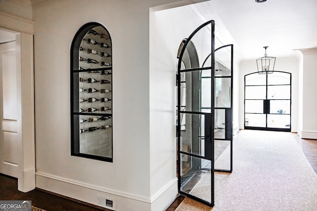 hallway with an inviting chandelier and dark carpet