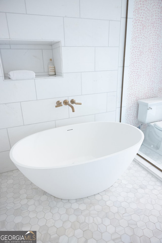 bathroom featuring toilet, tile patterned flooring, and a tub