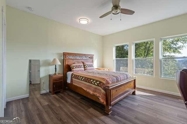 bedroom featuring ceiling fan, dark hardwood / wood-style floors, and multiple windows