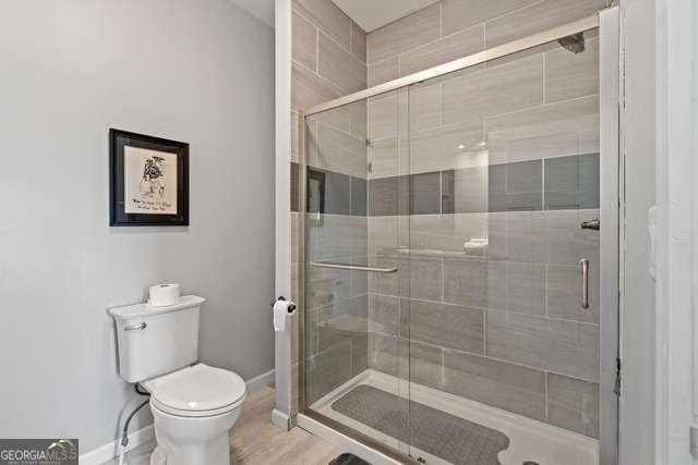 bathroom with a shower with shower door and toilet