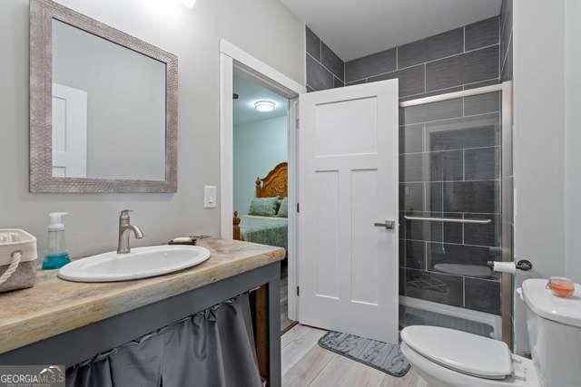 bathroom featuring a tile shower, hardwood / wood-style floors, toilet, and vanity