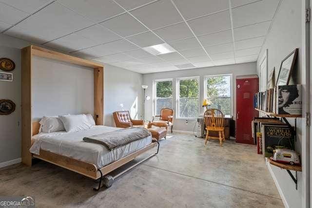 bedroom featuring concrete flooring and a drop ceiling